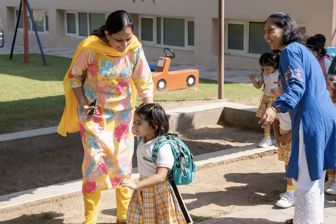 A teacher and a parent with a child in the garden