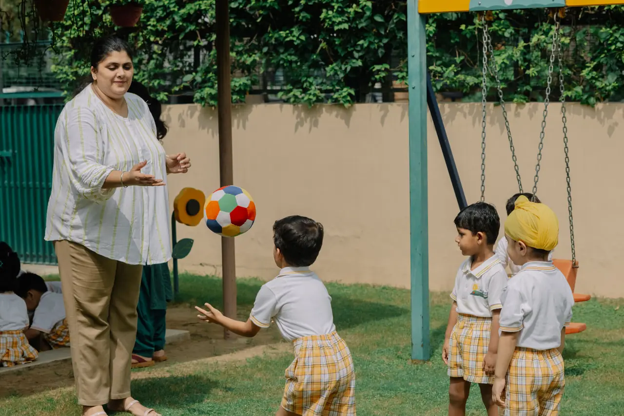 A teacher playing with children in the play pen