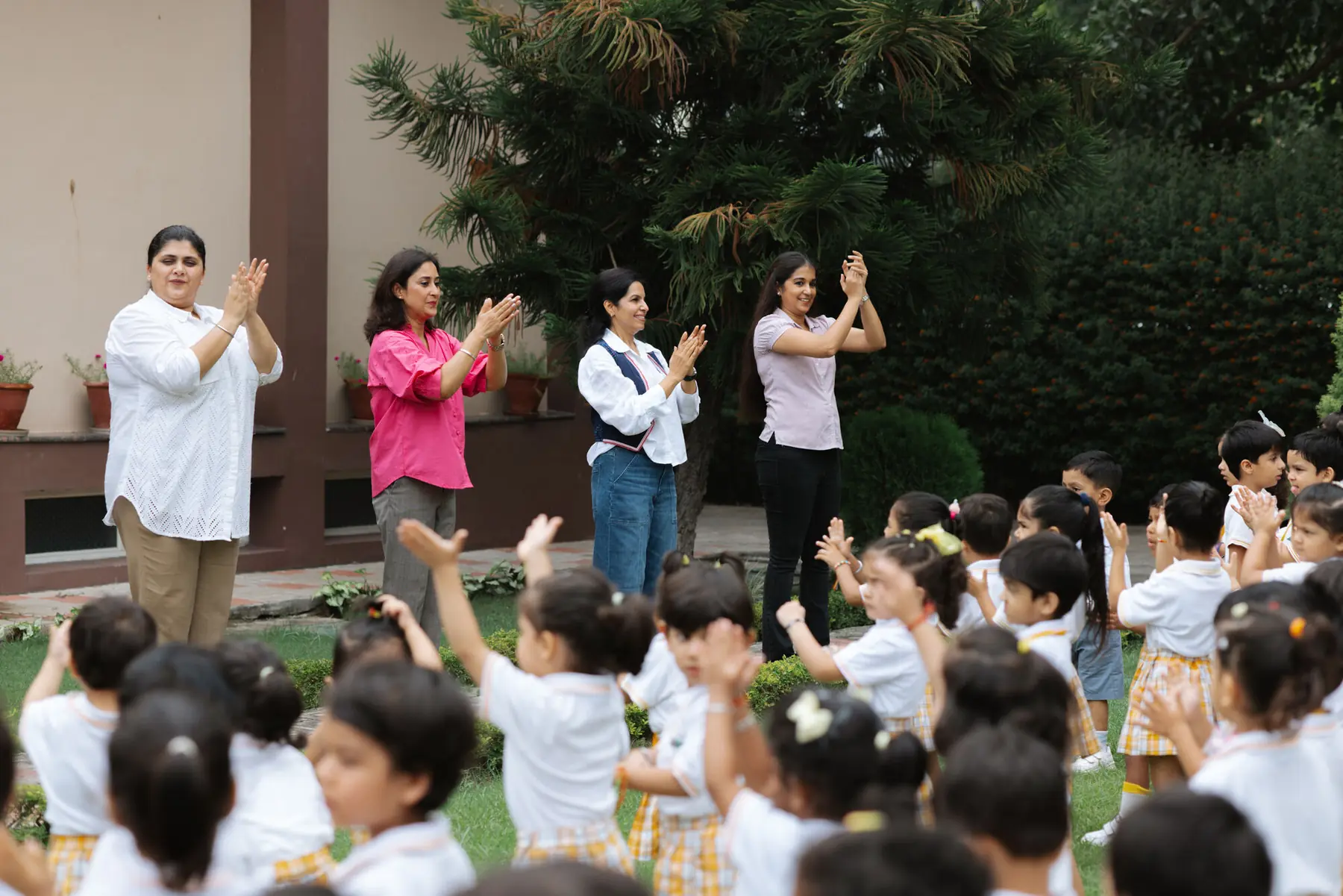 Teachers leading the children in an activity on the lawn